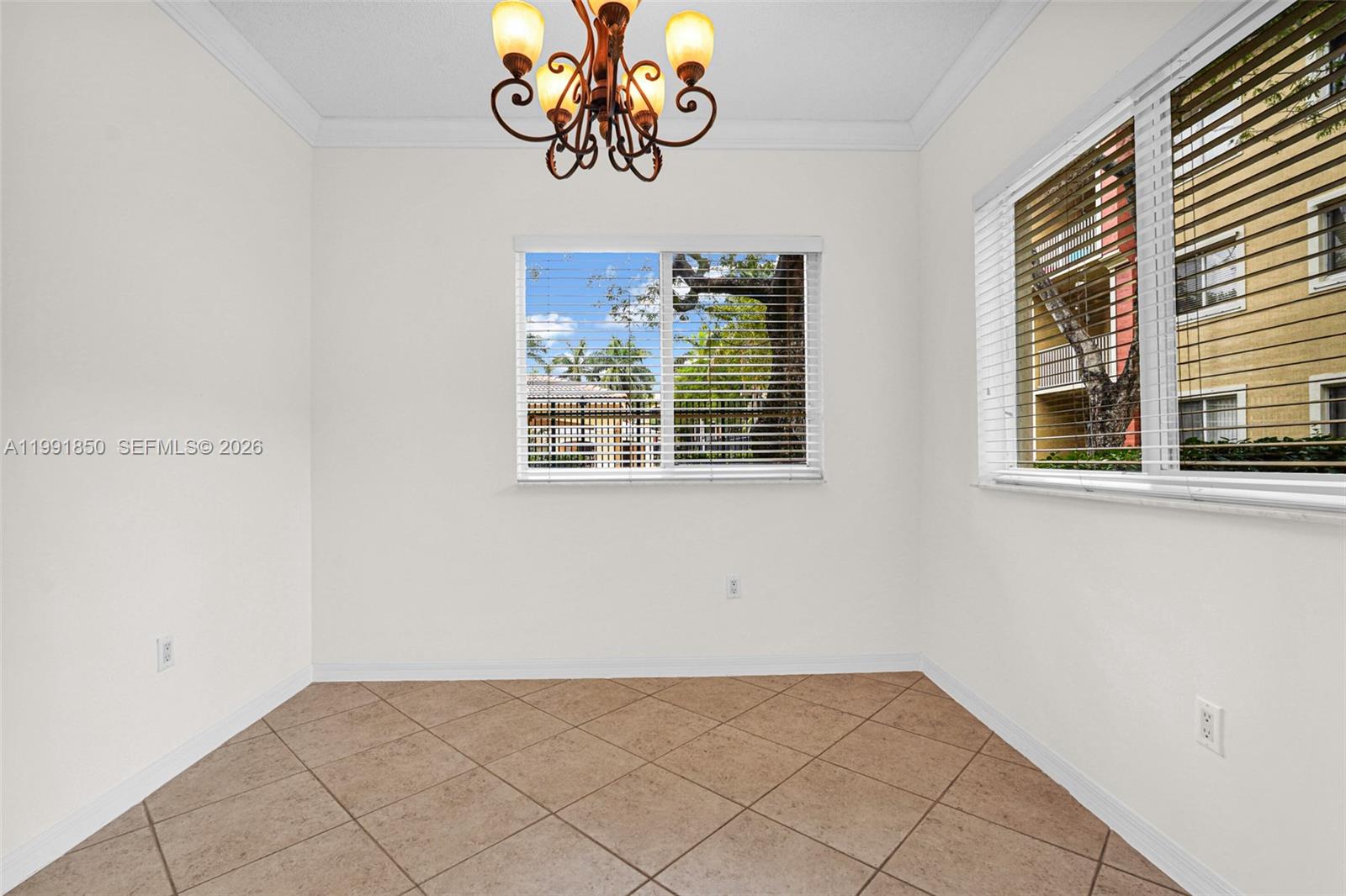 An empty dining area features tile flooring, a chandelier, and windows with white blinds — 7085 Nova Dr # 128, Davie FL 33317, DAVIE, FL