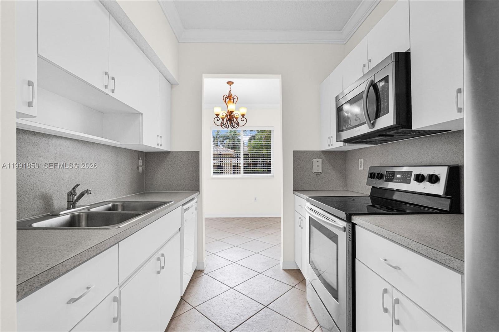 A galley kitchen features white cabinets, stainless steel appliances, and gray countertops — 7085 Nova Dr # 128, Davie FL 33317, DAVIE, FL