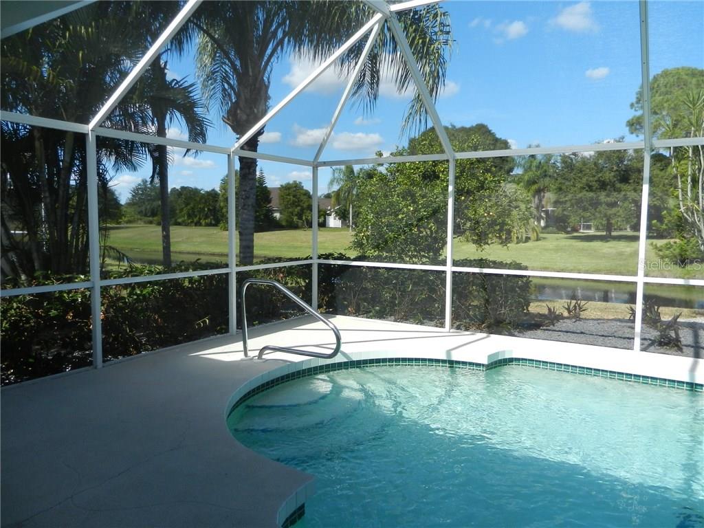 A screened-in pool area features a curved entry with a metal handrail overlooking a pond — 589 ROTONDA CIRCLE, ROTONDA WEST, FL