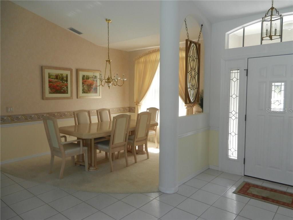 A dining room with a table and chairs sits adjacent to a tiled entryway — 589 ROTONDA CIRCLE, ROTONDA WEST, FL