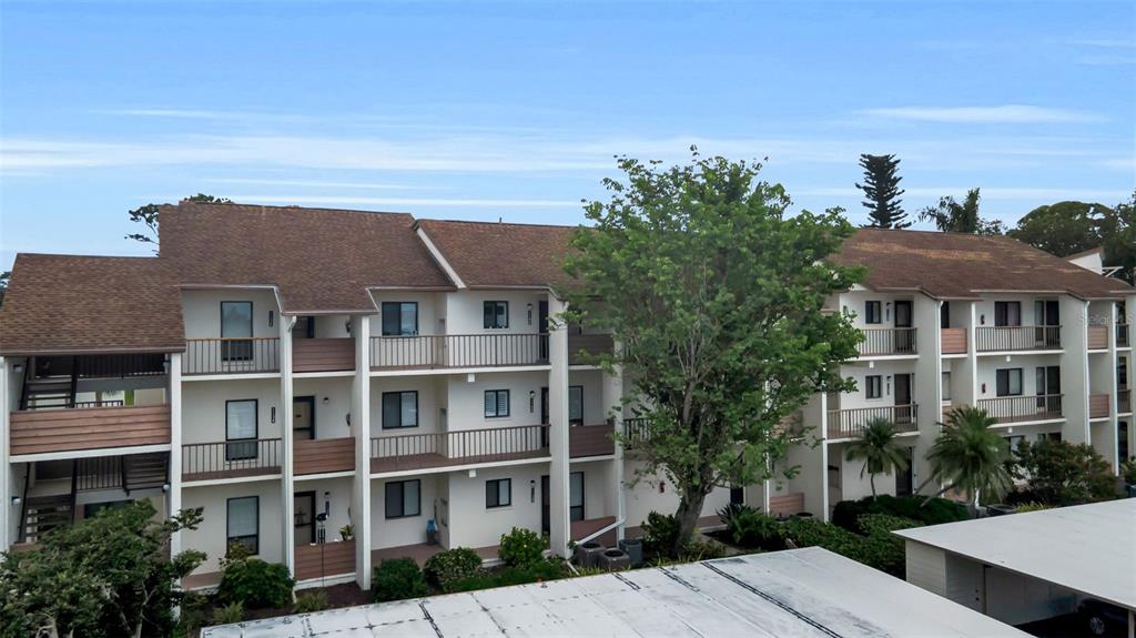 A three-story apartment building with balconies and a brown shingled roof under a blue sky — 1142 BIRD BAY WAY UNIT 301, VENICE, FL