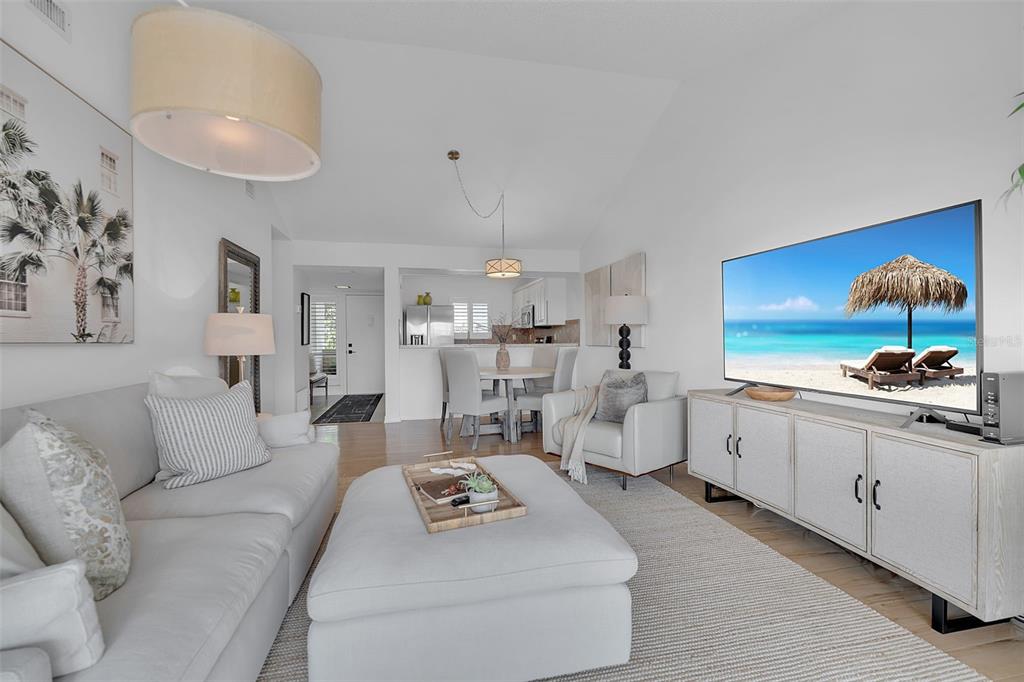 A living room features a white sofa, a large ottoman, and a television on a cabinet — 1142 BIRD BAY WAY UNIT 301, VENICE, FL