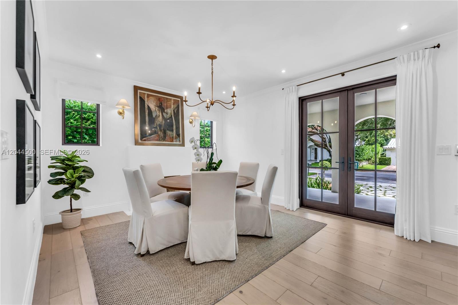 A dining room features a round wooden table, white slipcovered chairs, and French doors — 5730 SW 49th St, South Miami FL 33155, SOUTH MIAMI, FL