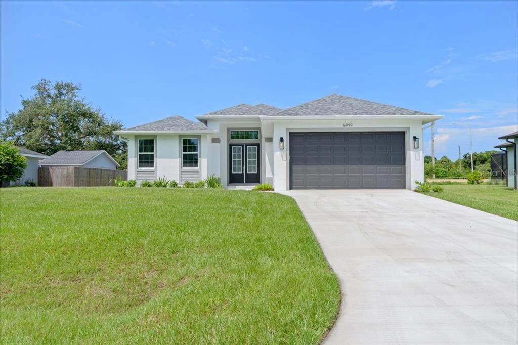 A single-story house with a white exterior, gray roof, and a two-car garage — 6999 BURNSVILLE STREET, ENGLEWOOD, FL