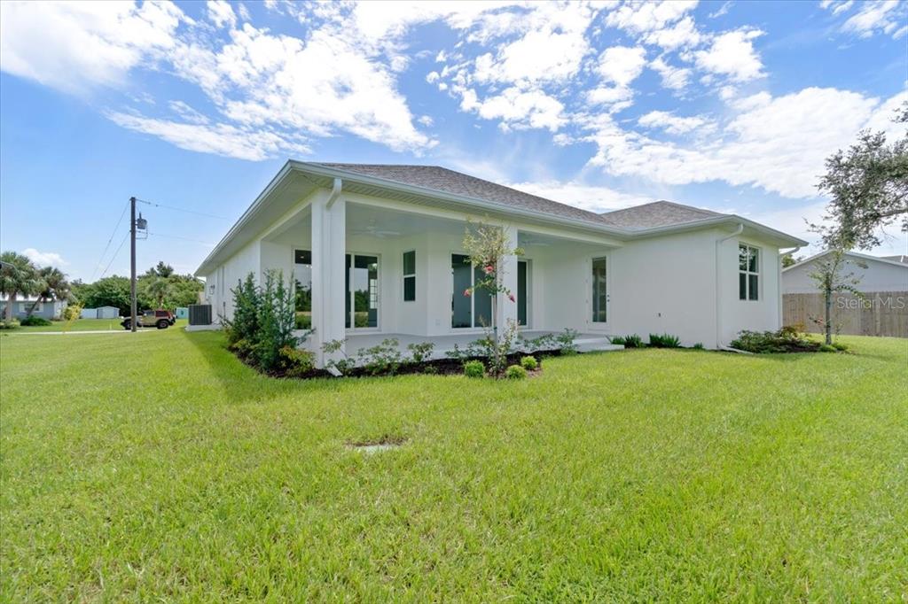 The exterior of a white house features a covered back patio and a large lawn — 6999 BURNSVILLE STREET, ENGLEWOOD, FL