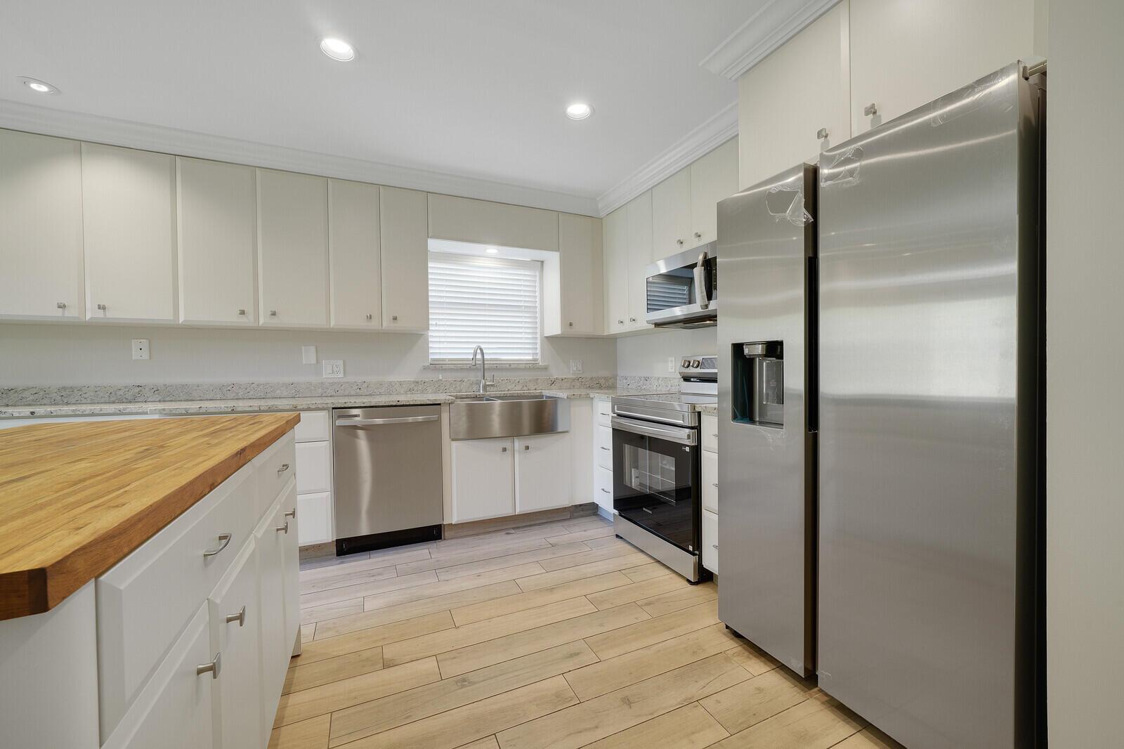 A kitchen with white cabinets, stainless steel appliances, granite countertops, and wood-look tile flooring — 683 Dover Street # 685, Boca Raton FL 33487, BOCA RATON, FL