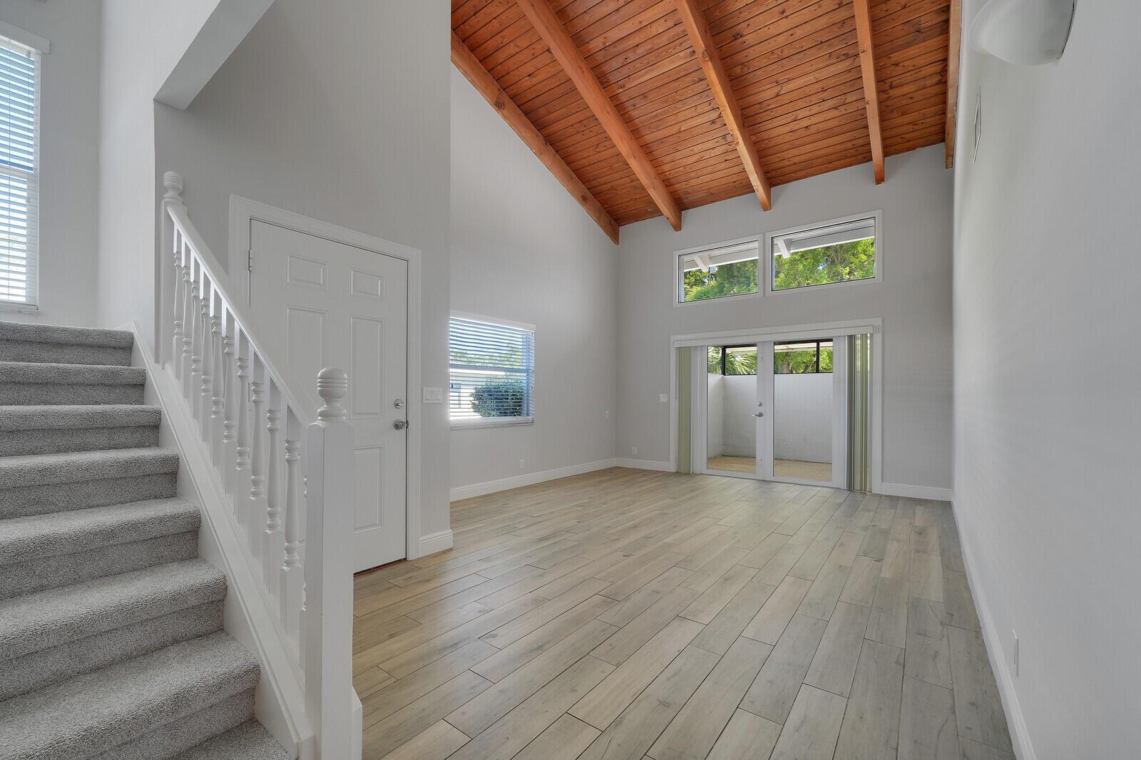 A living room features light wood-look flooring, a vaulted wood-plank ceiling, and a carpeted staircase — 683 Dover Street # 685, Boca Raton FL 33487, BOCA RATON, FL