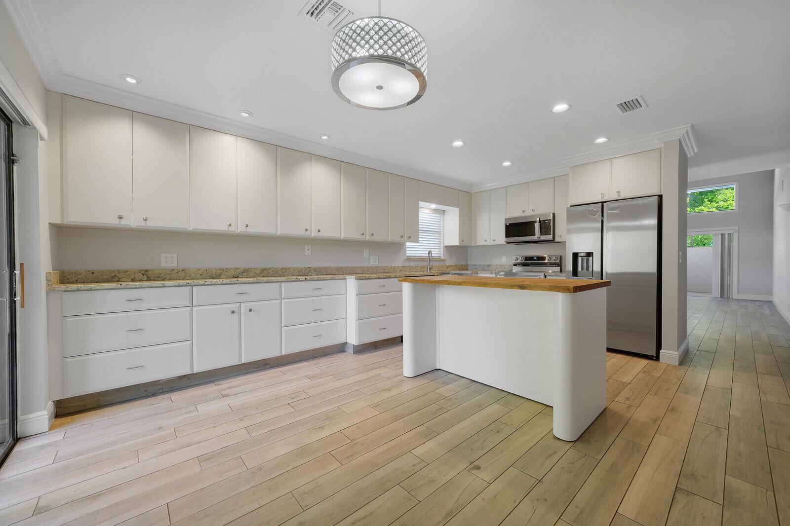 A kitchen with white cabinets, granite countertops, a wooden island, and light wood-look flooring — 683 Dover Street # 685, Boca Raton FL 33487, BOCA RATON, FL