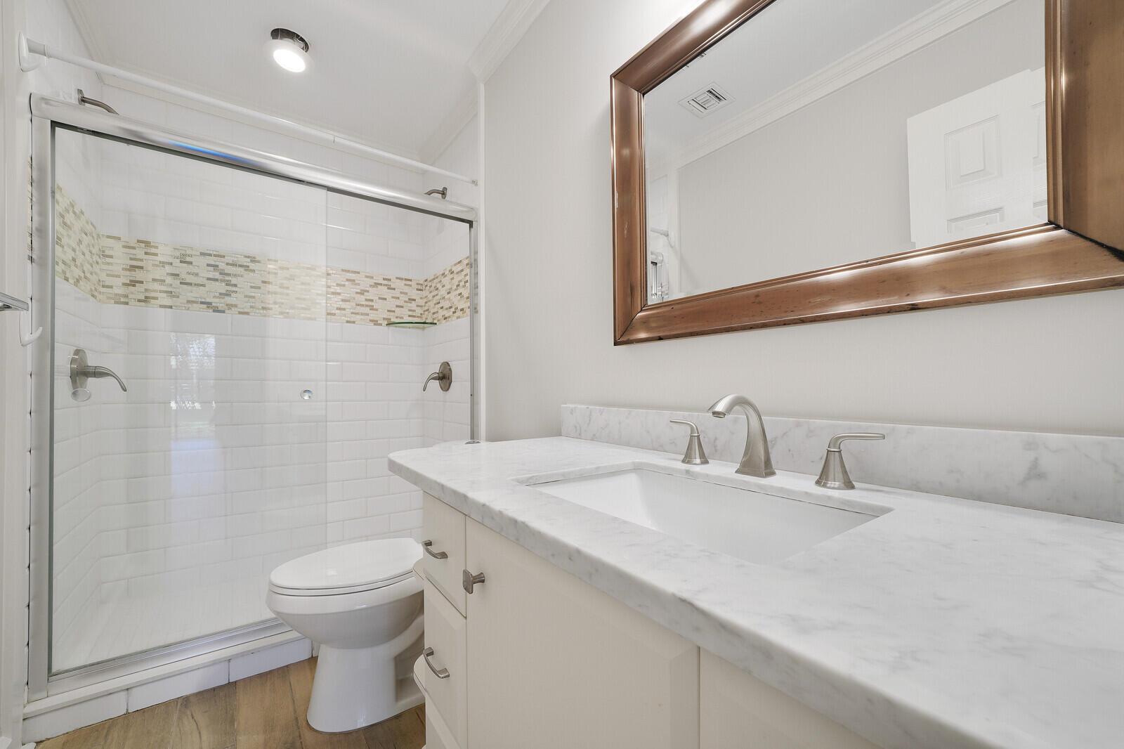 A bathroom features a marble-topped vanity, a glass-enclosed shower, and a toilet — 683 Dover Street # 685, Boca Raton FL 33487, BOCA RATON, FL