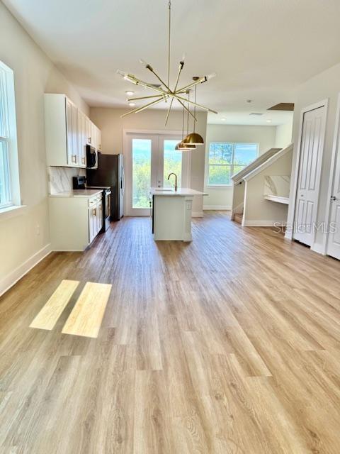 A kitchen with white cabinets, a central island, and light wood-look flooring — 1612 BIRCHFIELD COVE, OVIEDO, FL