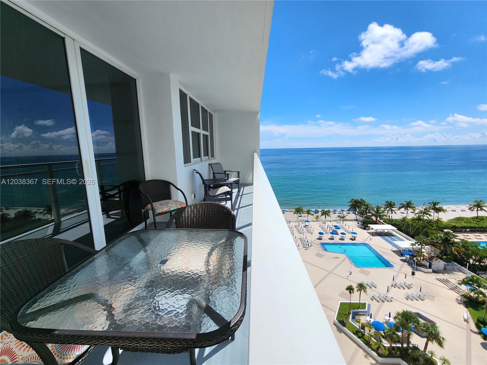 A balcony with patio furniture overlooks a swimming pool, beach, and the ocean — 2030 S Ocean Dr # 1718, Hallandale Beach FL 33009, HALLANDALE BEACH, FL
