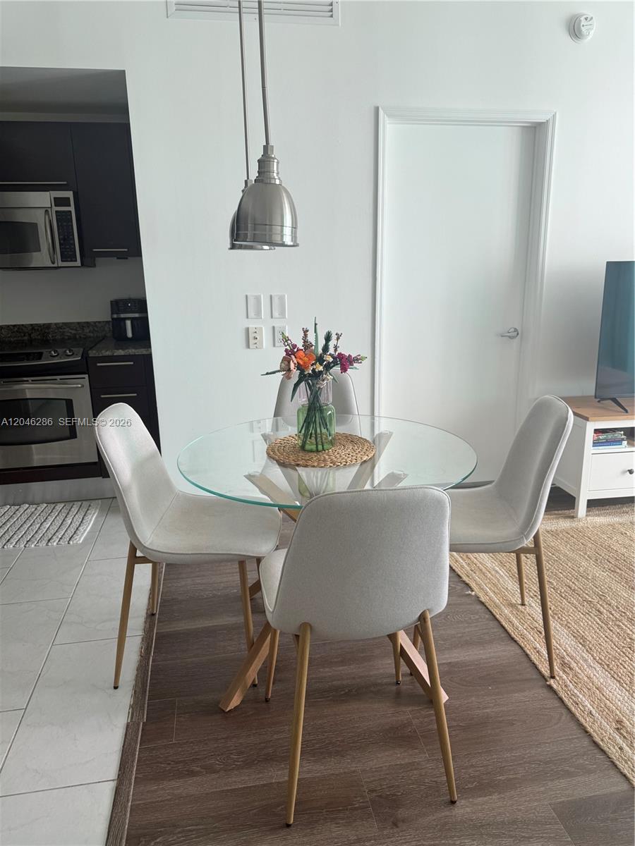 A dining area features a glass-topped table with four chairs next to a kitchen — 950 Brickell Bay Dr # 2907, Miami FL 33131, MIAMI, FL