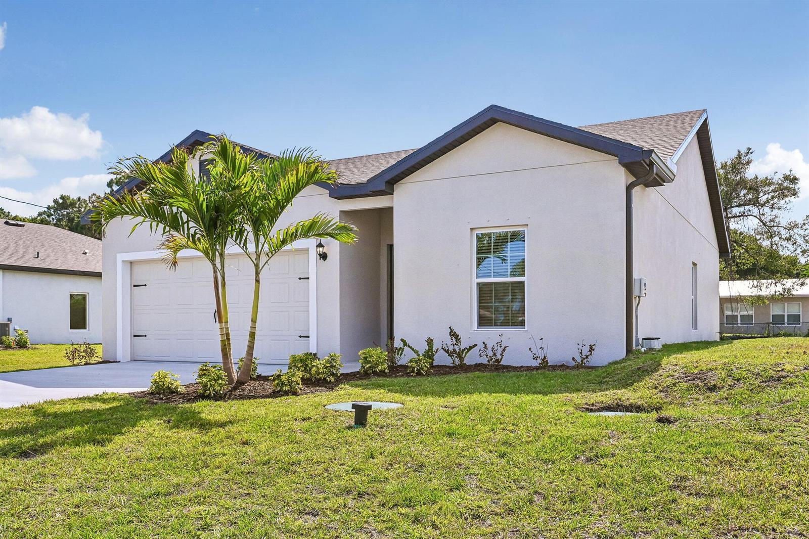 A single-story house with a white stucco exterior, a two-car garage, and a palm tree — 5709 Sunset Boulevard, Fort Pierce FL 34982, FORT PIERCE, FL