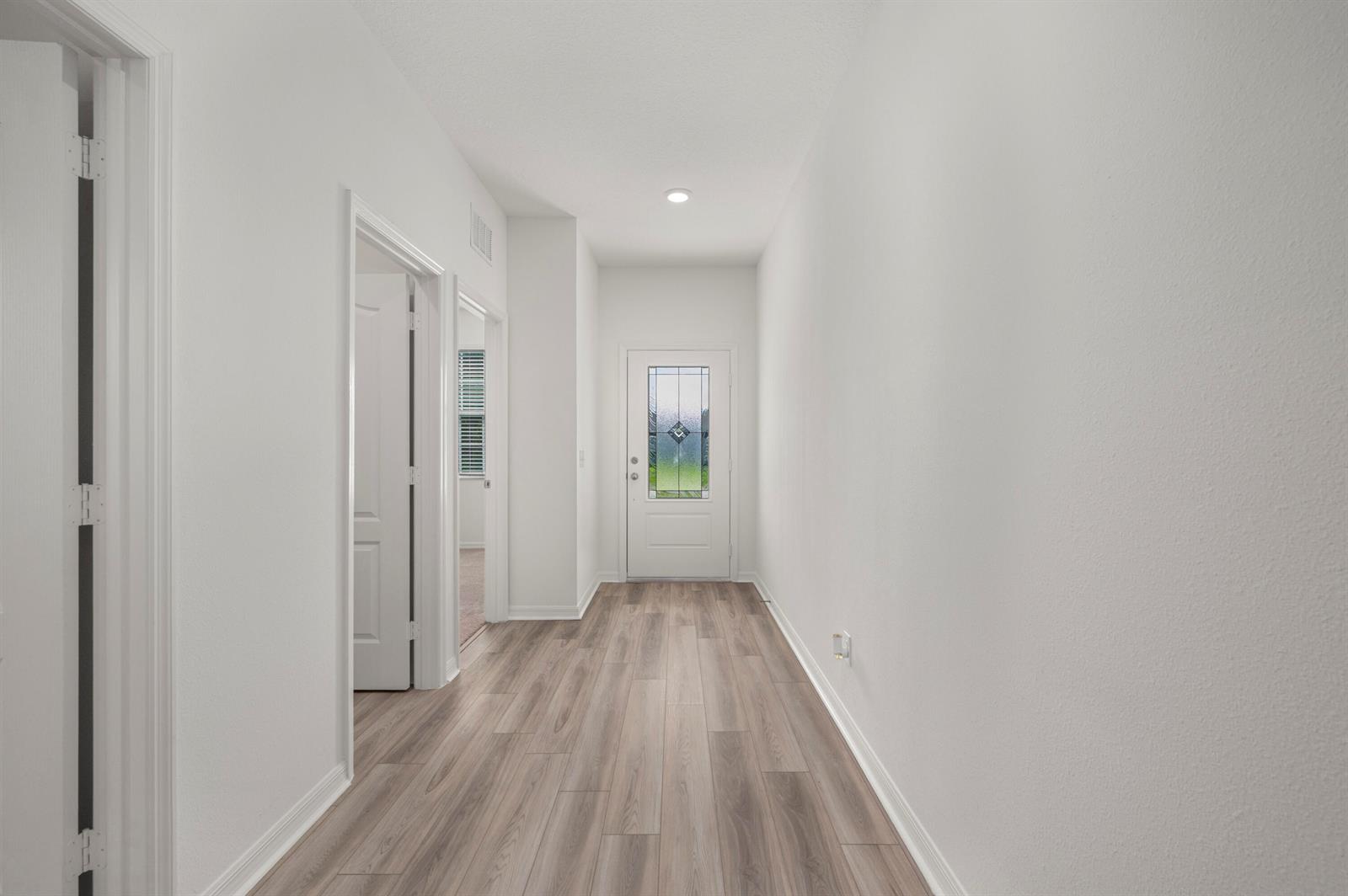 A bright hallway features white walls, light wood-look flooring, and a glass-paneled front door — 5709 Sunset Boulevard, Fort Pierce FL 34982, FORT PIERCE, FL