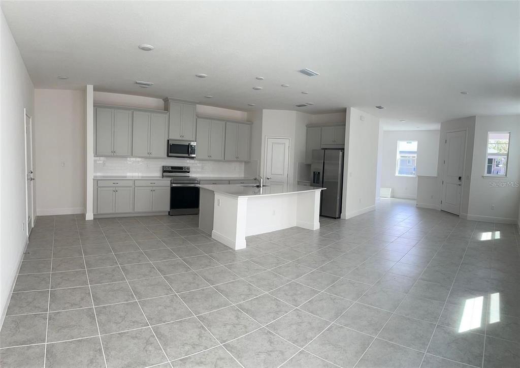 A kitchen with light gray cabinets, a white island, and tile flooring in an open space — 4806 PRAIRIE PRESERVE RUN, ST CLOUD, FL