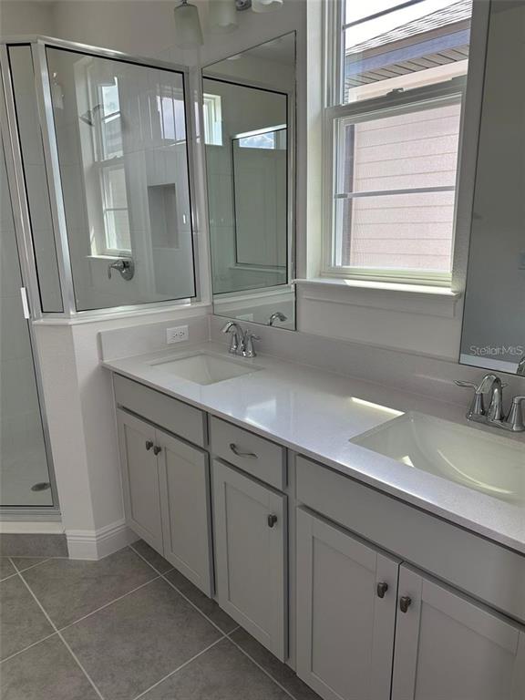 A bathroom features a double vanity with light gray cabinets, white countertops, and a glass shower — 4806 PRAIRIE PRESERVE RUN, ST CLOUD, FL