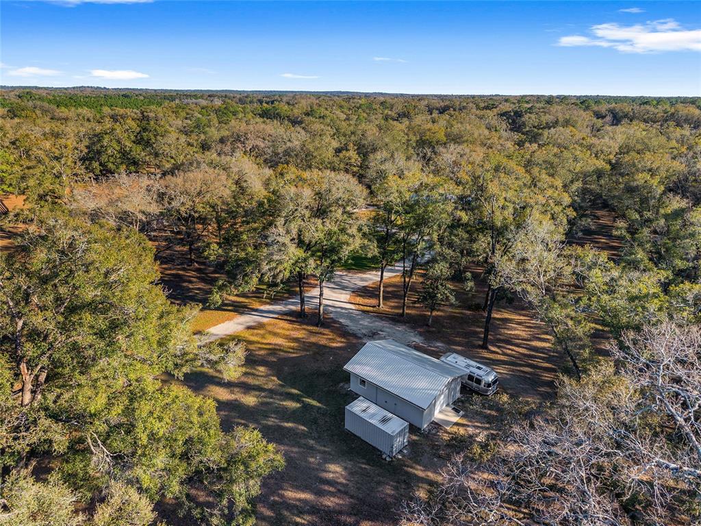 An aerial view shows a metal building and a trailer situated in a wooded lot — 6012 NW 168TH STREET, ALACHUA, FL