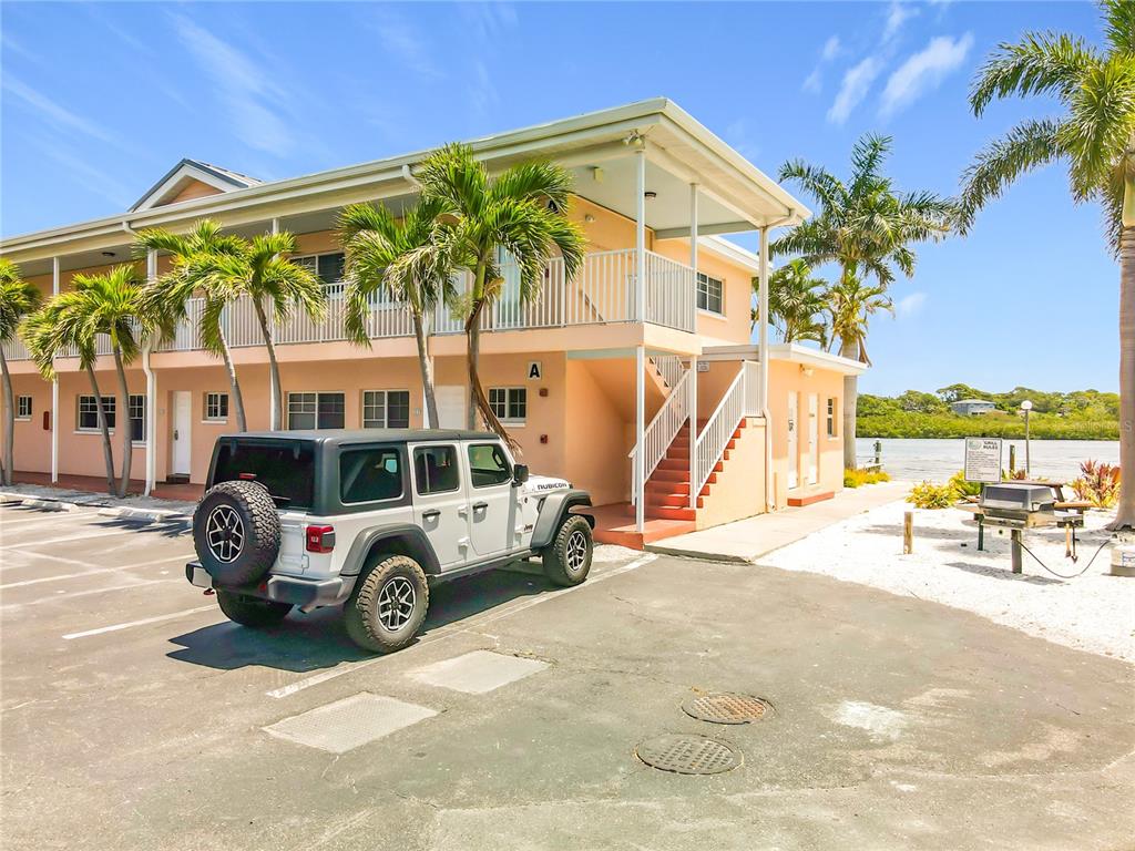 A two-story peach-colored building with a parked Jeep Rubicon in the foreground — 19417 GULF BOULEVARD UNIT A-113, INDIAN SHORES, FL