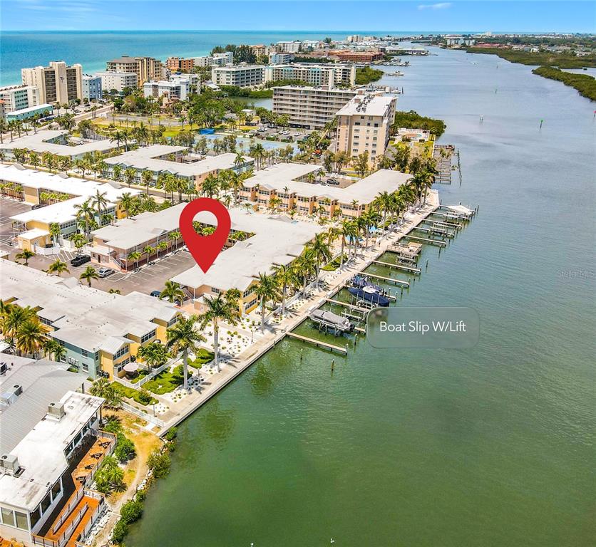 An aerial view shows a waterfront condominium complex with a boat slip and lift — 19417 GULF BOULEVARD UNIT A-113, INDIAN SHORES, FL
