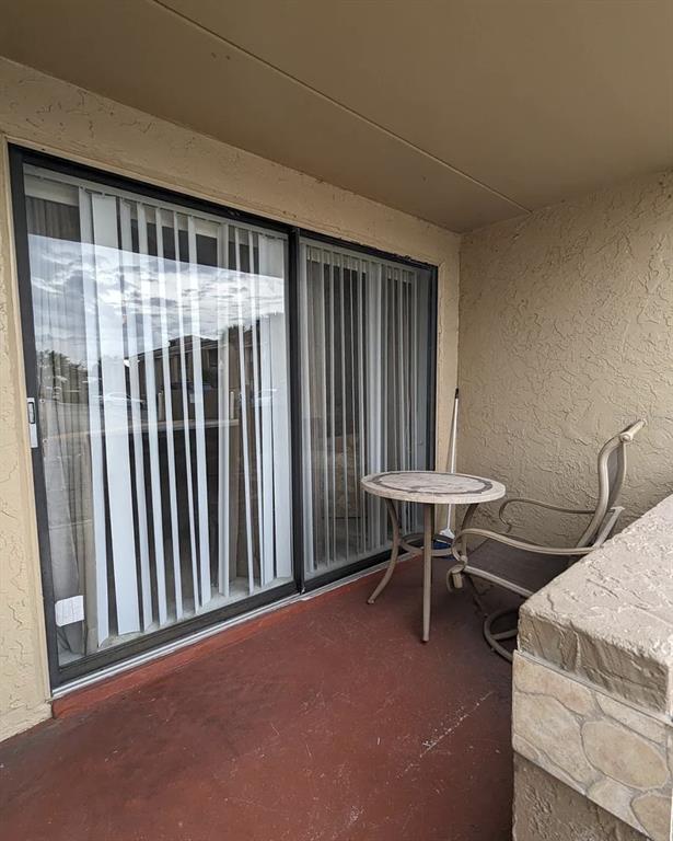A small balcony features a round table, a chair, and a sliding glass door — 5229 VINELAND ROAD UNIT A106, ORLANDO, FL