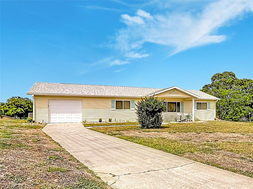 A single-story yellow house with a concrete driveway and a white garage door — 8121 SW 107TH PLACE, OCALA, FL