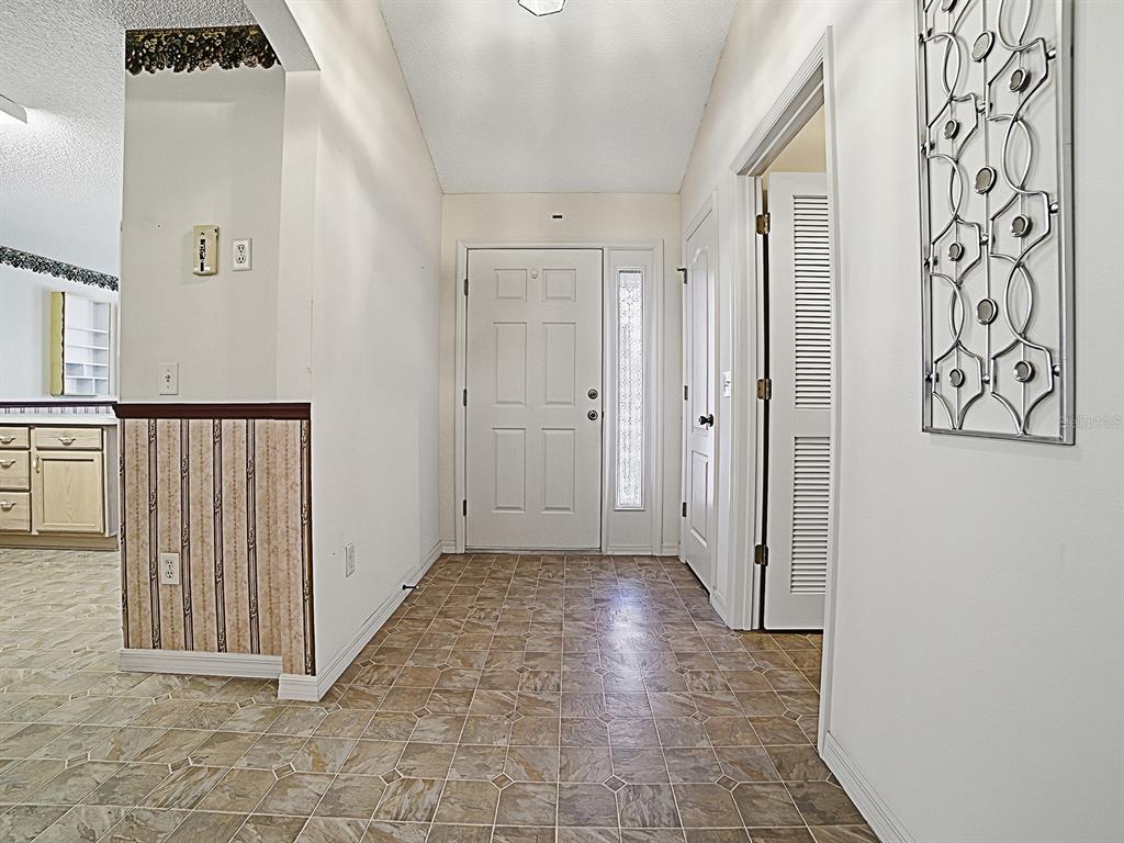 The entryway features a white front door, tiled flooring, and wallpapered walls — 16865 SE 93RD CUTHBERT CIRCLE, THE VILLAGES, FL