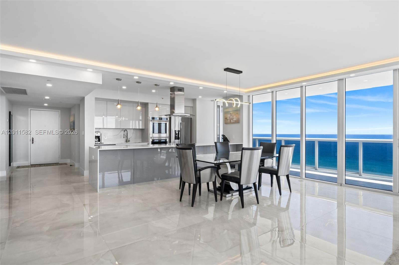 A modern open-concept kitchen and dining area features glossy tile floors and floor-to-ceiling ocean views — 1830 S Ocean Dr # 1002, Hallandale Beach FL 33009, HALLANDALE BEACH, FL