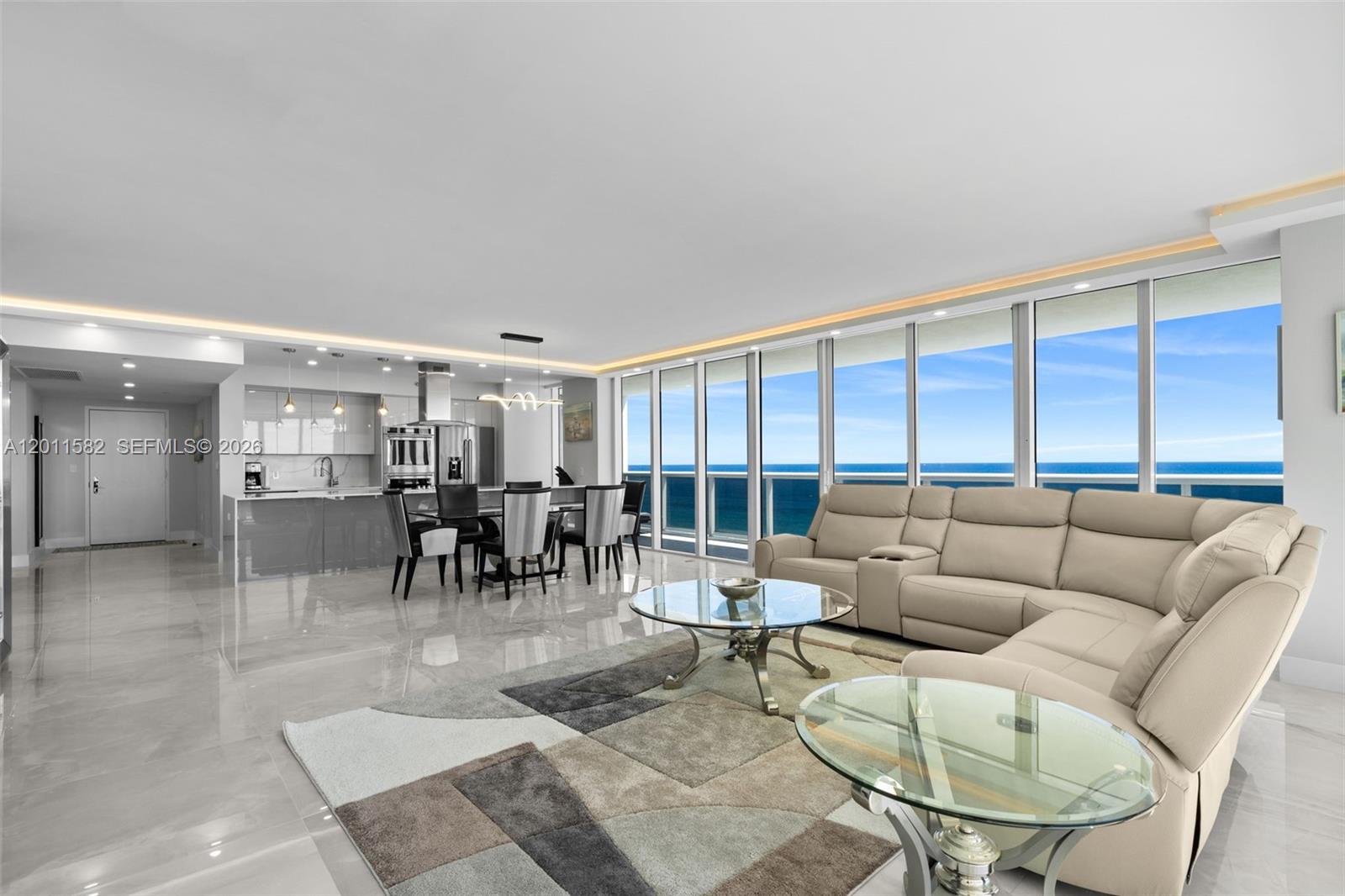 A modern open-concept living and dining area features tile floors and floor-to-ceiling ocean views — 1830 S Ocean Dr # 1002, Hallandale Beach FL 33009, HALLANDALE BEACH, FL