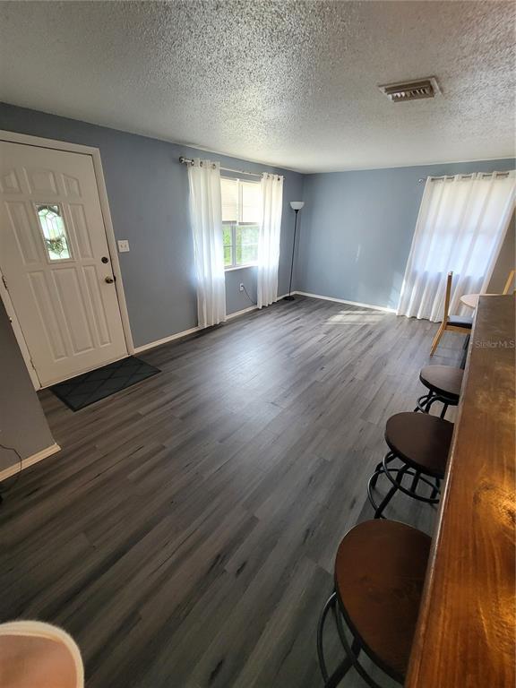 A living room with light blue walls, wood-look flooring, white curtains, and a breakfast bar — 10061 61ST WAY N, PINELLAS PARK, FL