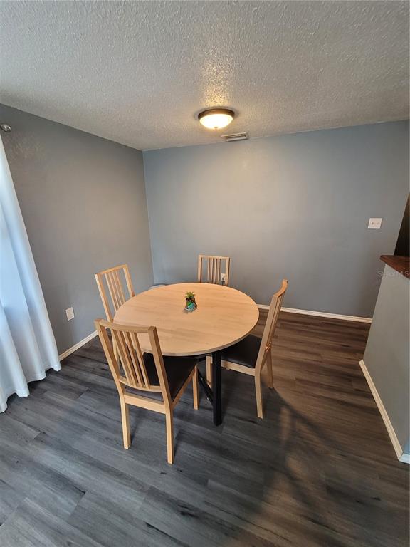 A dining area features a round wooden table, four chairs, and gray wood-look flooring — 10061 61ST WAY N, PINELLAS PARK, FL