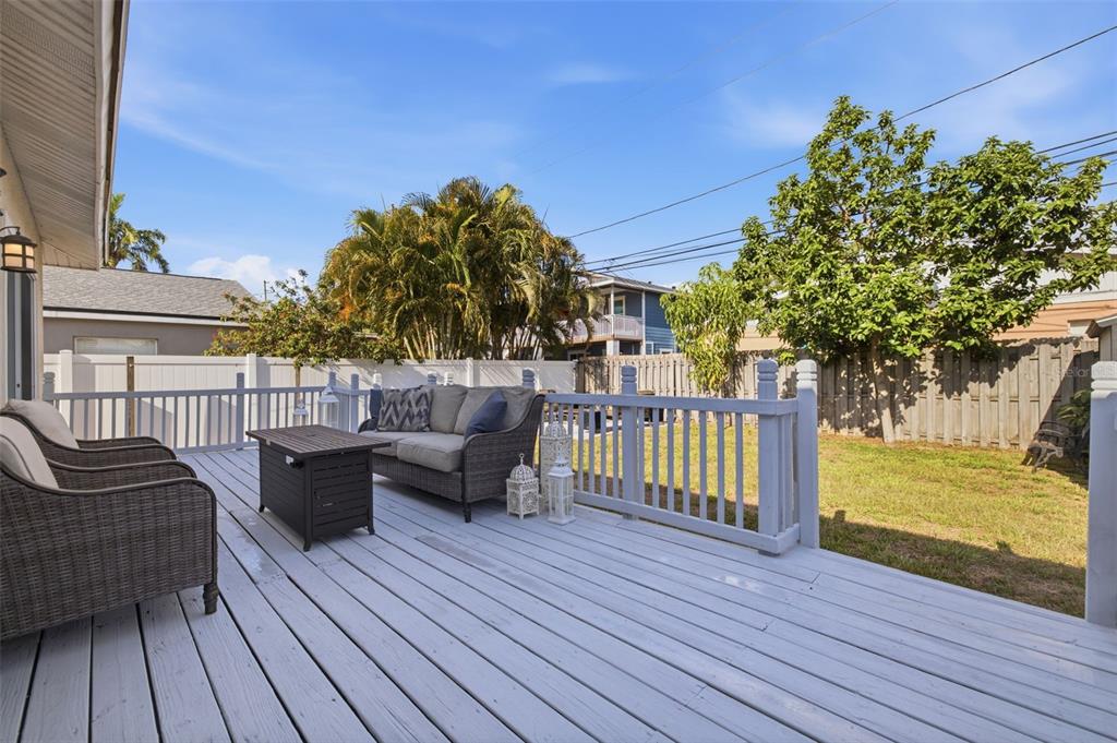 A wooden deck features outdoor furniture, a fire pit, and a fenced backyard with trees — 3110 15TH STREET N, ST PETERSBURG, FL