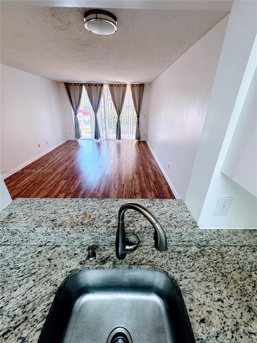 A galley-style kitchen features white cabinets, granite countertops, stainless steel appliances, and a stacked washer-dryer — 1341 SE 3rd Ave # 112, Dania Beach FL 33004, DANIA BEACH, FL