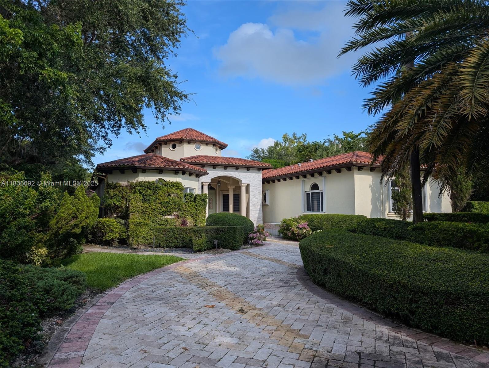 A single-story house with a tiled roof, arched entryway, and a paved driveway — 13400 SW 83rd Ave, Pinecrest FL 33156, PINECREST, FL