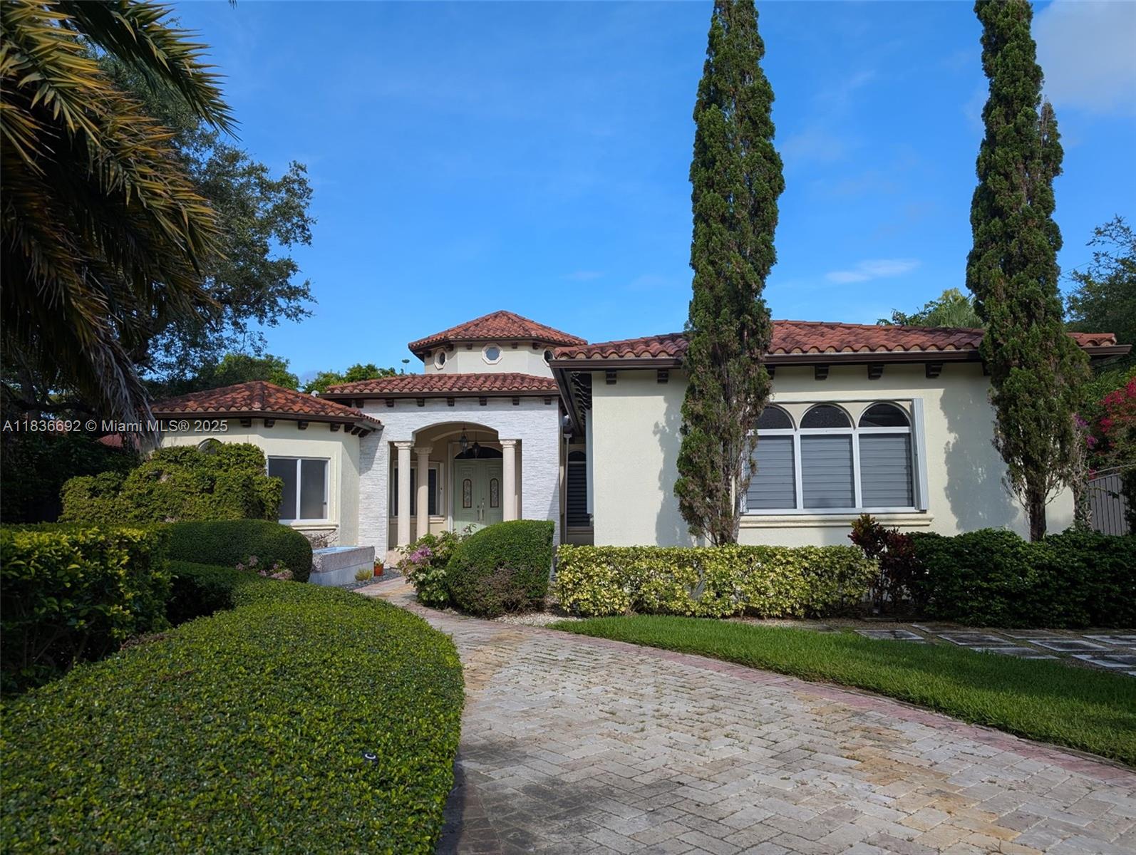 A single-story Mediterranean-style house features a tiled roof, arched windows, and a stone-paved driveway — 13400 SW 83rd Ave, Pinecrest FL 33156, PINECREST, FL