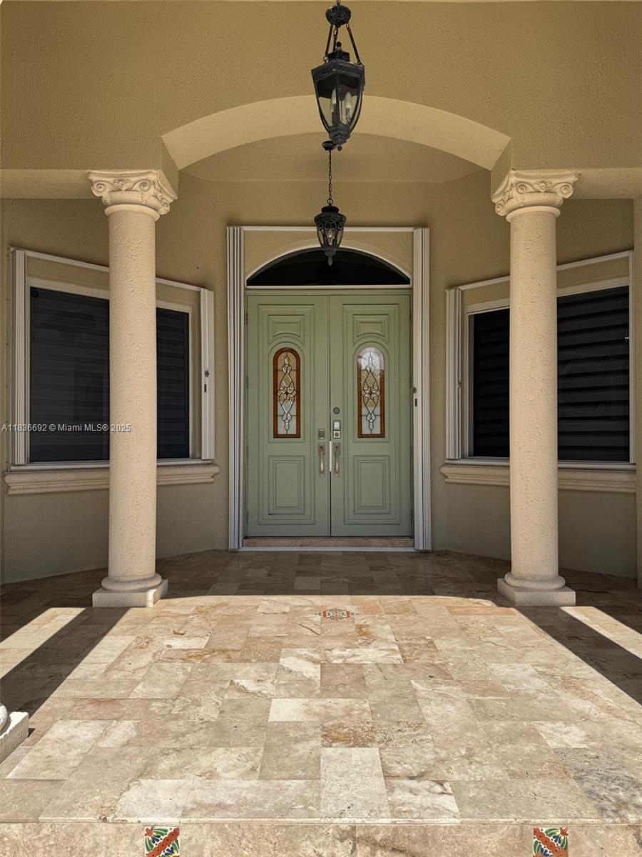 A stone-tiled entryway features two columns, a light green double door, and hanging lanterns — 13400 SW 83rd Ave, Pinecrest FL 33156, PINECREST, FL