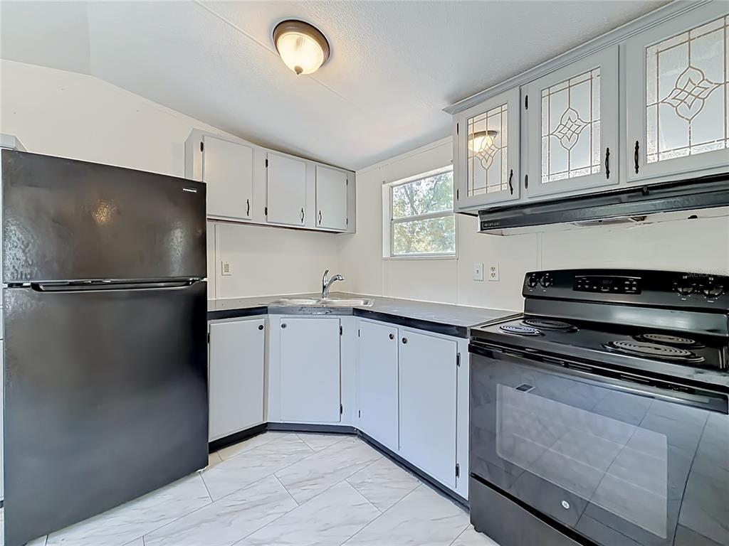 A kitchen features light gray cabinets, black appliances, and white marble-patterned tile flooring — 14671 SE 25TH STREET, MORRISTON, FL