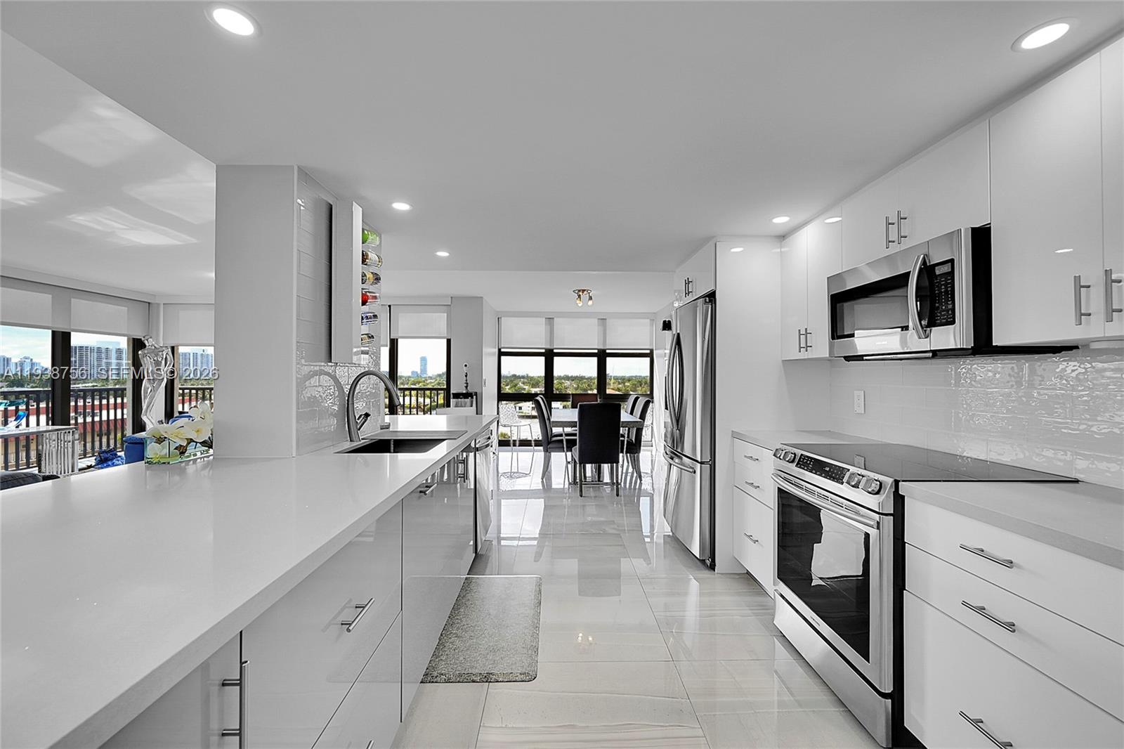 A modern open-concept living room features a grey sectional, kitchen island, and tile flooring — 2049 S Ocean Dr # 701, Hallandale Beach FL 33009, HALLANDALE BEACH, FL