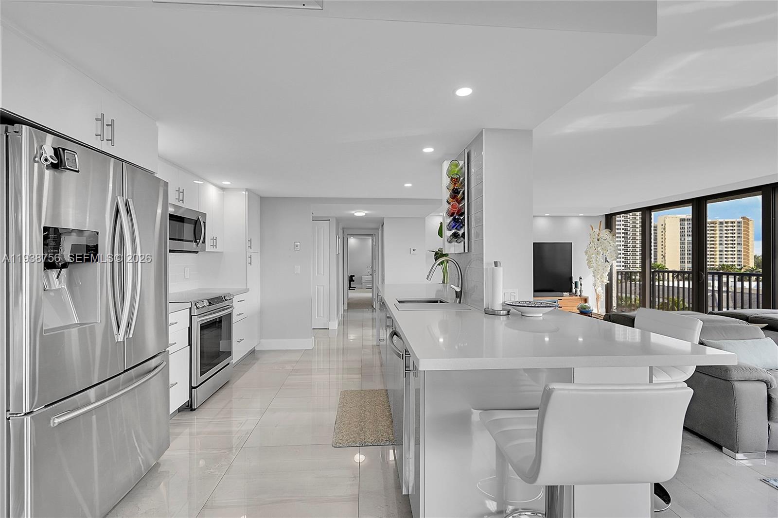A modern living room features a grey sectional sofa, a wooden coffee table, and floor-to-ceiling windows — 2049 S Ocean Dr # 701, Hallandale Beach FL 33009, HALLANDALE BEACH, FL