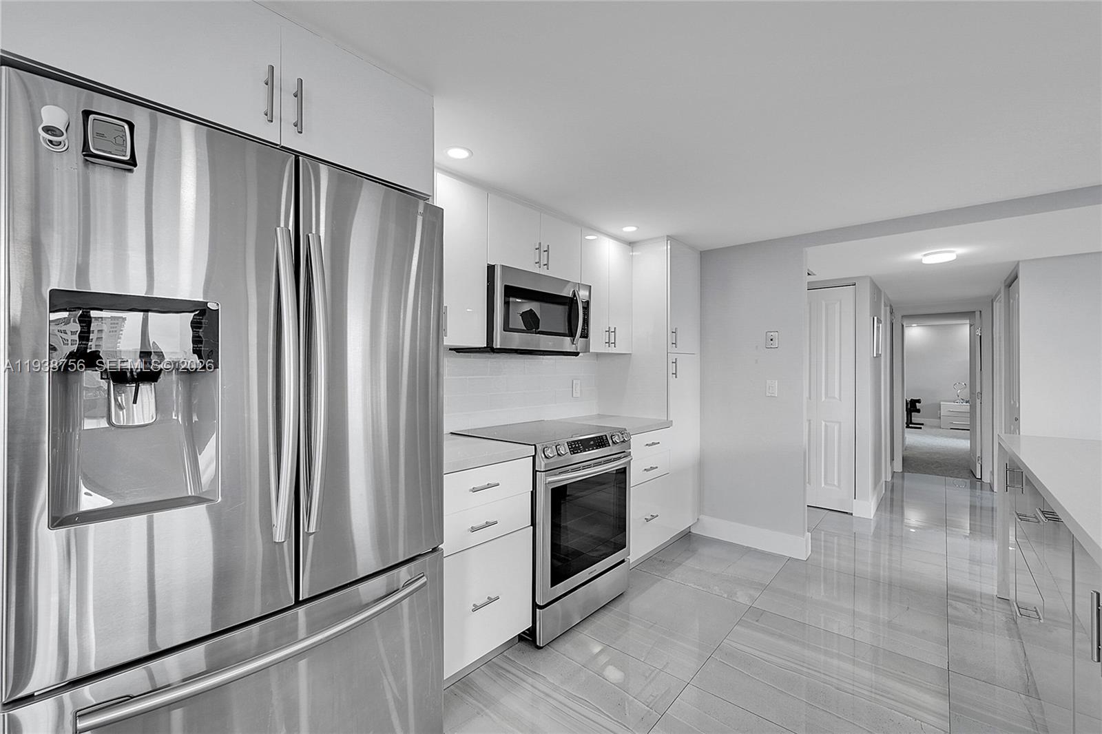 An open-concept living and dining area features a modern kitchen, gray sofa, and blue accents — 2049 S Ocean Dr # 701, Hallandale Beach FL 33009, HALLANDALE BEACH, FL