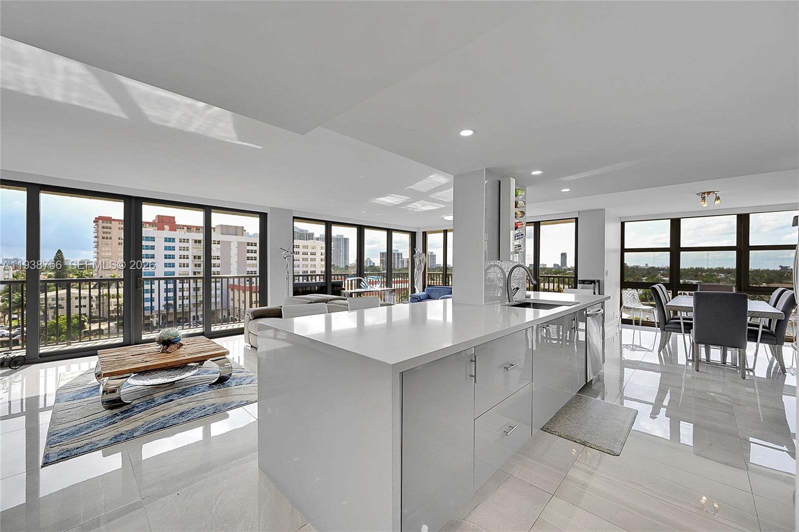 A dining area with a wooden table and grey chairs opens into a modern living space — 2049 S Ocean Dr # 701, Hallandale Beach FL 33009, HALLANDALE BEACH, FL