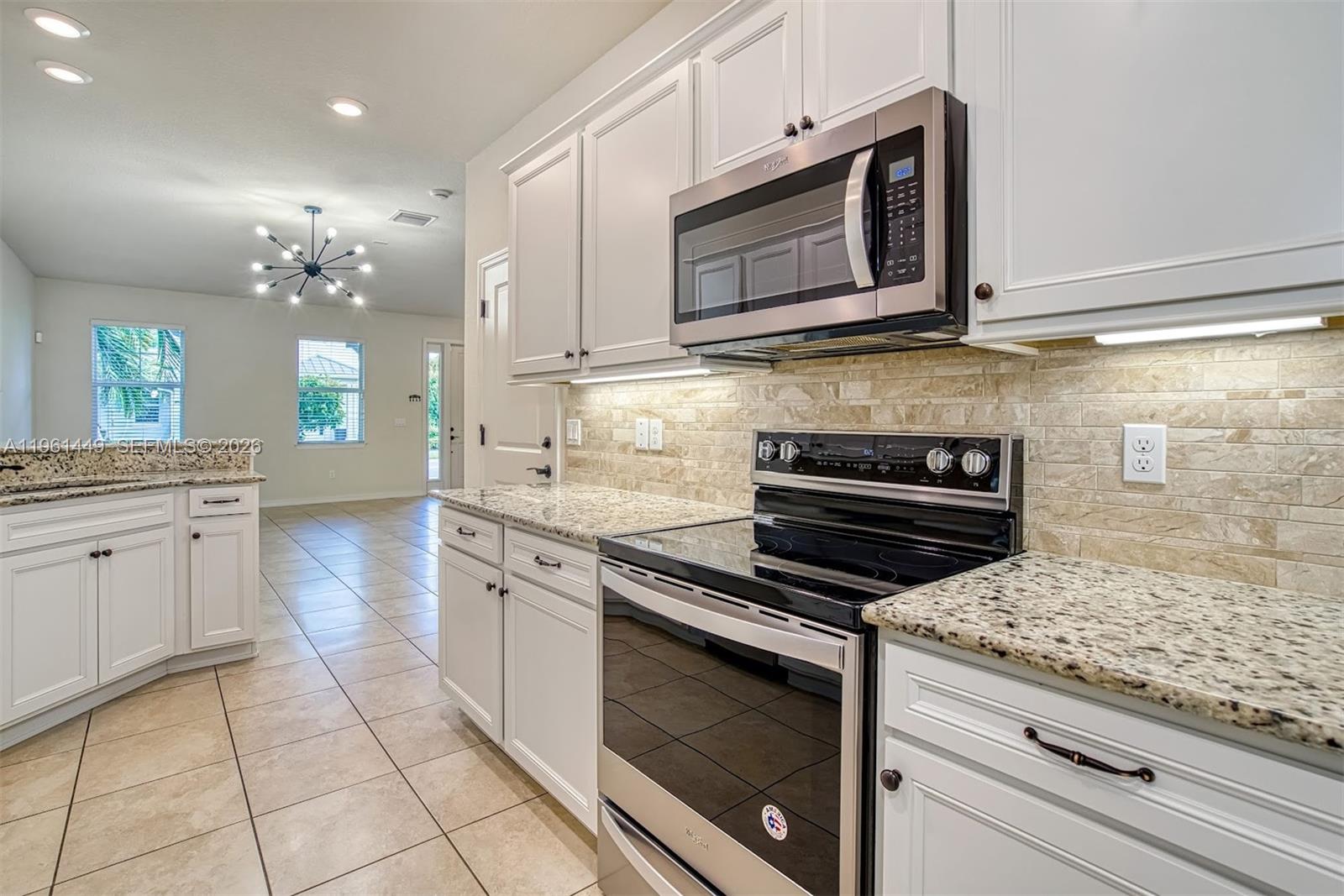 A kitchen features white cabinetry, granite countertops, stainless steel appliances, and a tiled backsplash — 5060 Eucalyptus Dr # 2, Hollywood FL 33021, HOLLYWOOD, FL