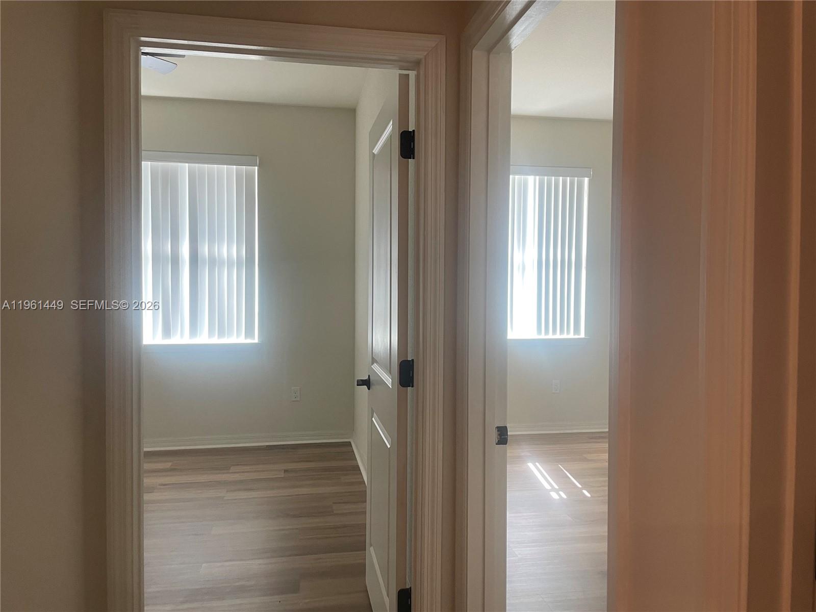 Two adjacent rooms with light-colored walls, wood-look flooring, and windows with vertical blinds — 5060 Eucalyptus Dr # 2, Hollywood FL 33021, HOLLYWOOD, FL