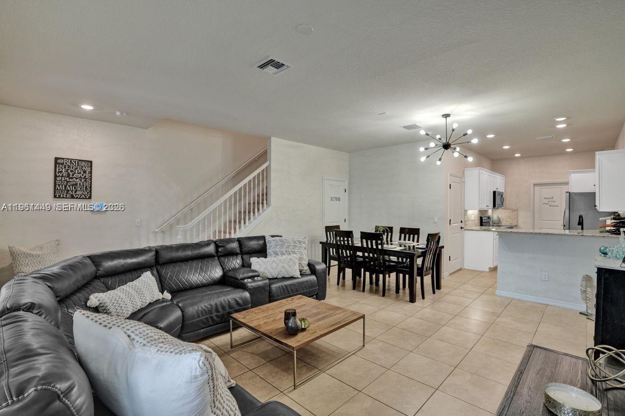 An open-concept living and dining area features tile flooring, a black sectional, and white cabinetry — 5060 Eucalyptus Dr # 2, Hollywood FL 33021, HOLLYWOOD, FL