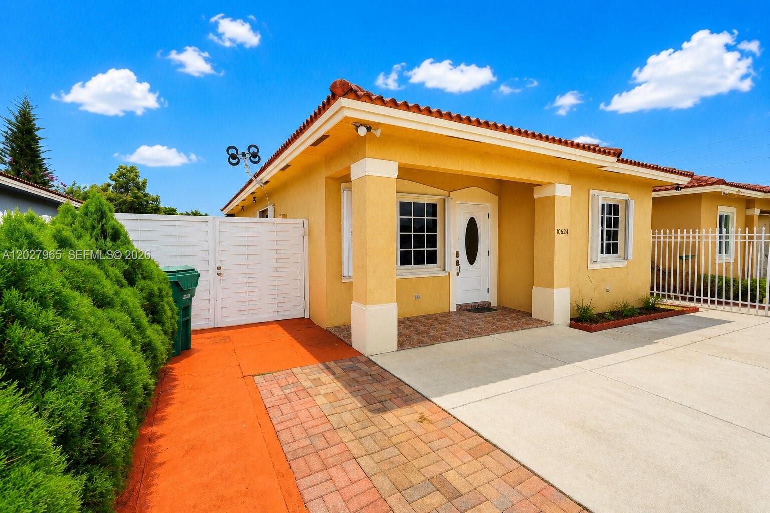 A yellow single-story house features a tiled roof, a covered porch, and a paved driveway — 10624 SW 181st St, Miami FL 33157, MIAMI, FL