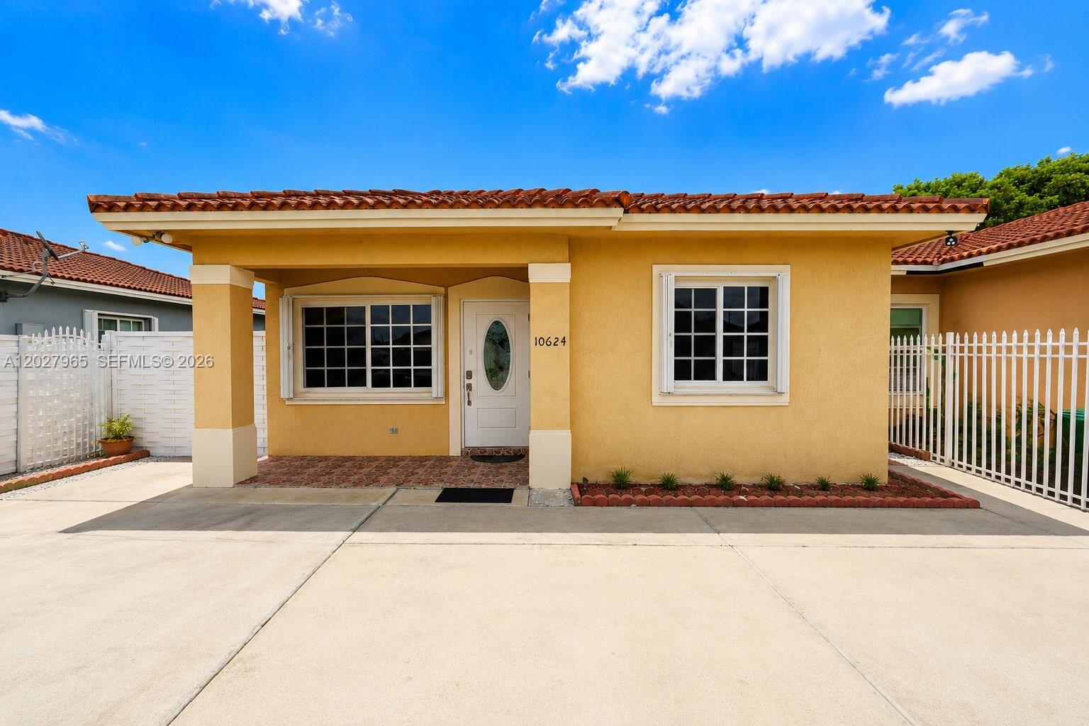 A yellow single-story house features a tiled roof, a covered entryway, and a concrete driveway — 10624 SW 181st St, Miami FL 33157, MIAMI, FL