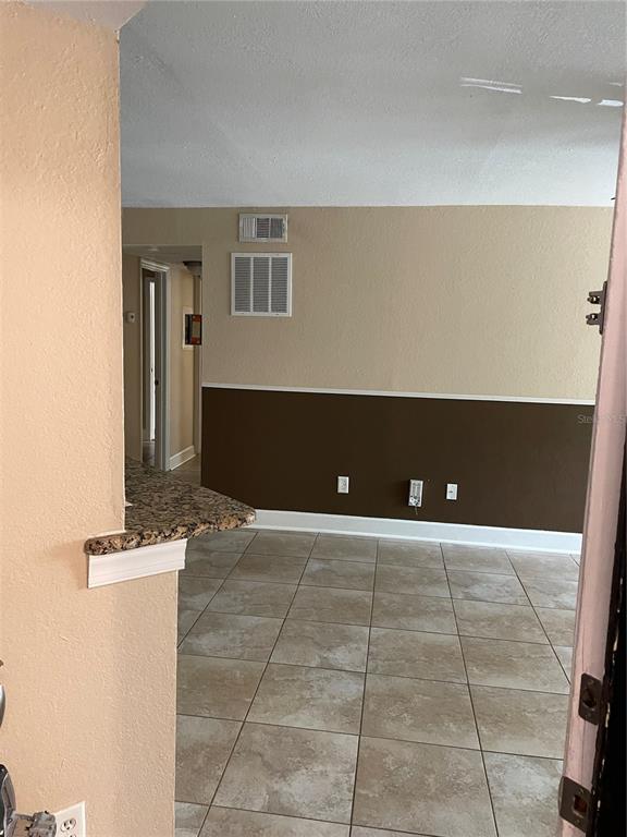 An interior view shows a tiled room with two-tone walls and a granite-topped breakfast bar — 4512 COMMANDER DRIVE UNIT 1725, ORLANDO, FL