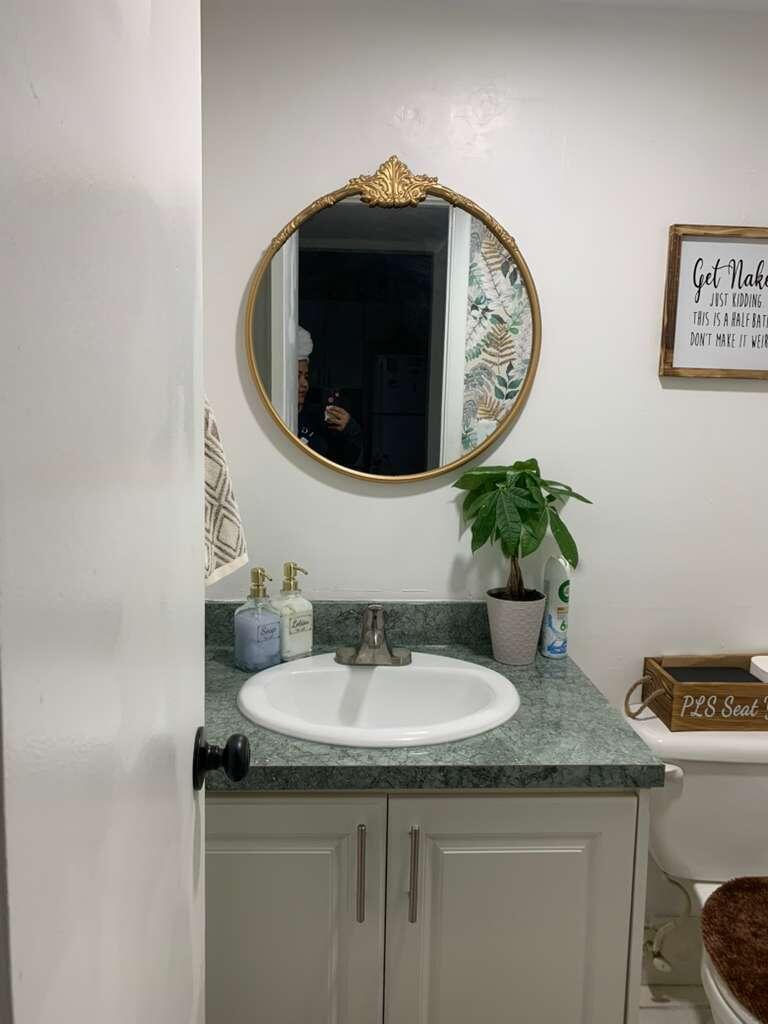 A small bathroom features a green laminate countertop, a round gold mirror, and a vanity — 13707 Kendale Lakes Circle, Miami FL 33183, MIAMI, FL