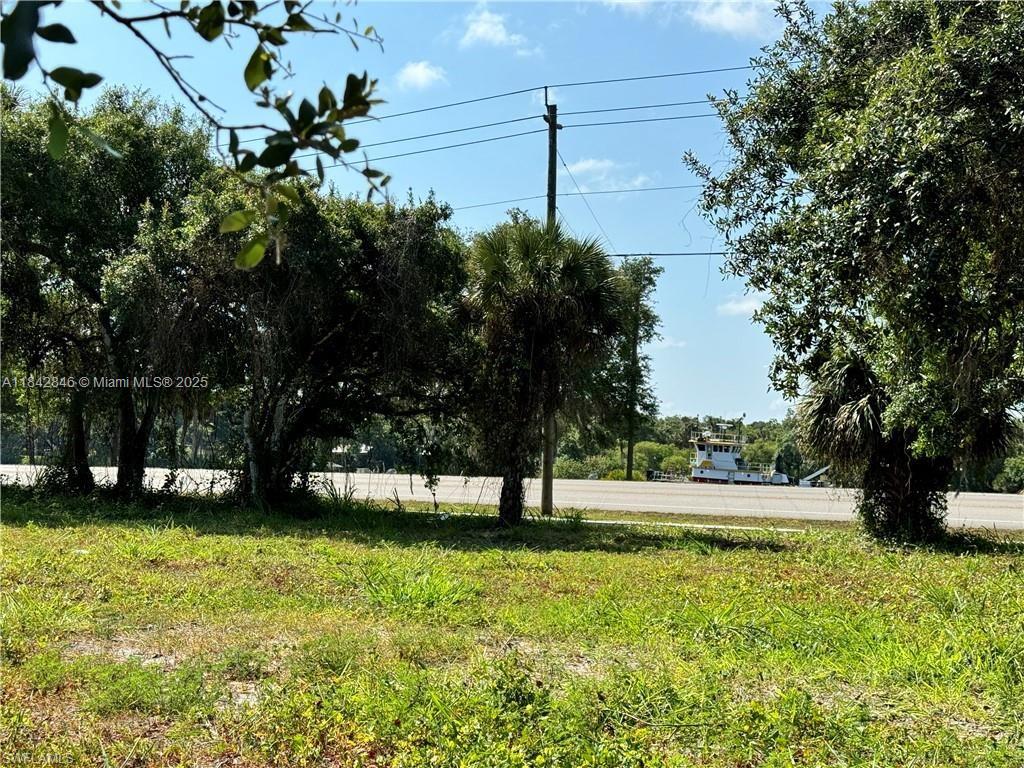 A grassy lot with trees and a utility pole overlooks a road and a boat — 500 Avalon Ave, La Belle FL 33935, LA BELLE, FL