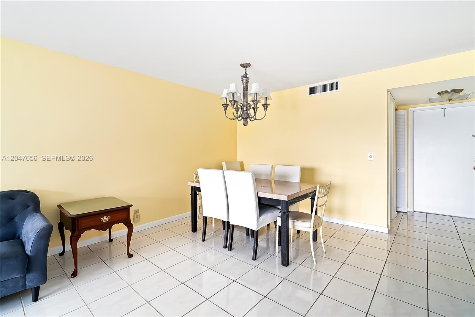 A dining room features yellow walls, white tile floors, a chandelier, and a table set — 4500 Gefion Ct # 304, Lake Worth FL 33467, LAKE WORTH, FL