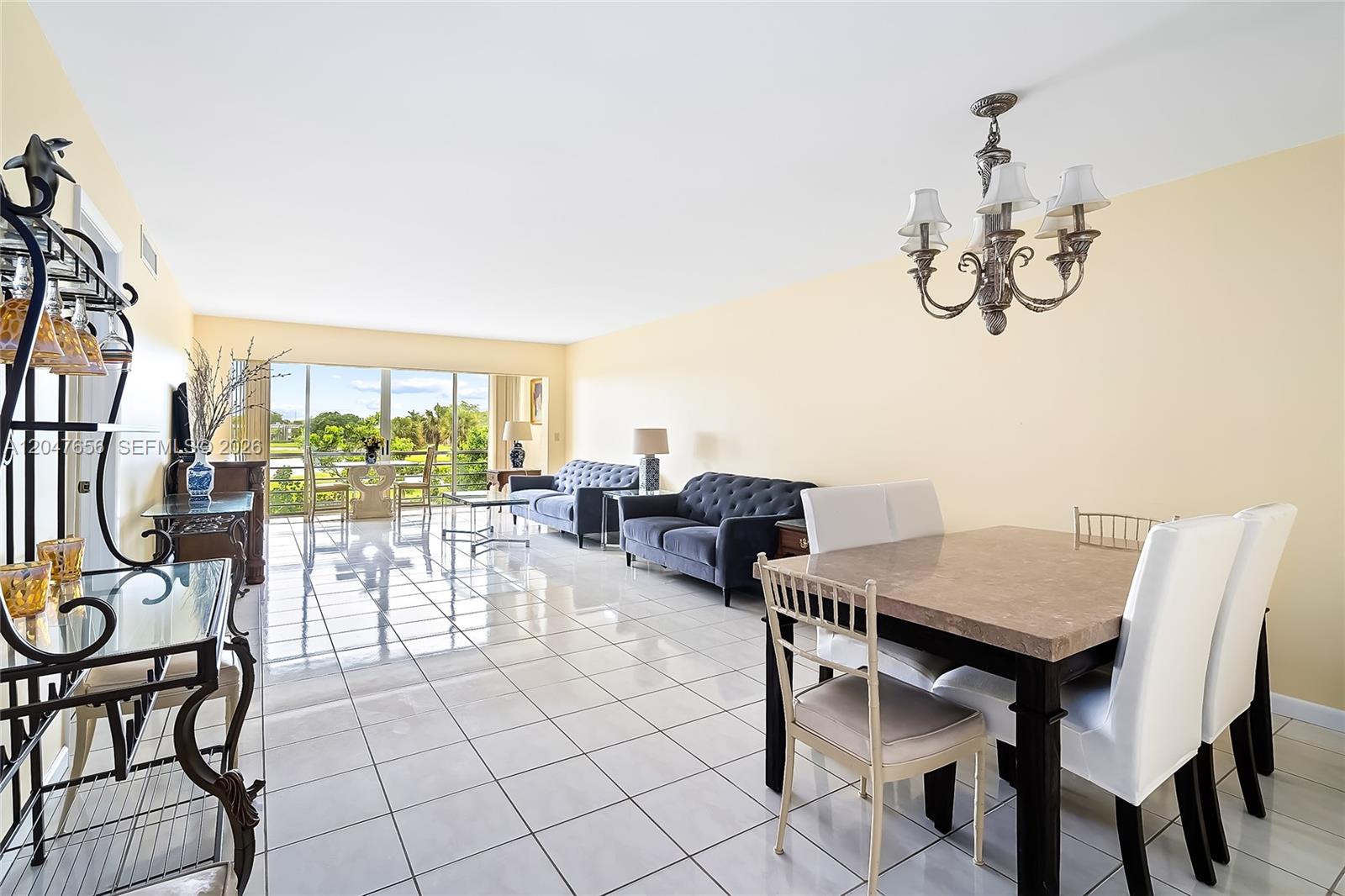 A bright living and dining area features white tile floors, two dark sofas, and a chandelier — 4500 Gefion Ct # 304, Lake Worth FL 33467, LAKE WORTH, FL